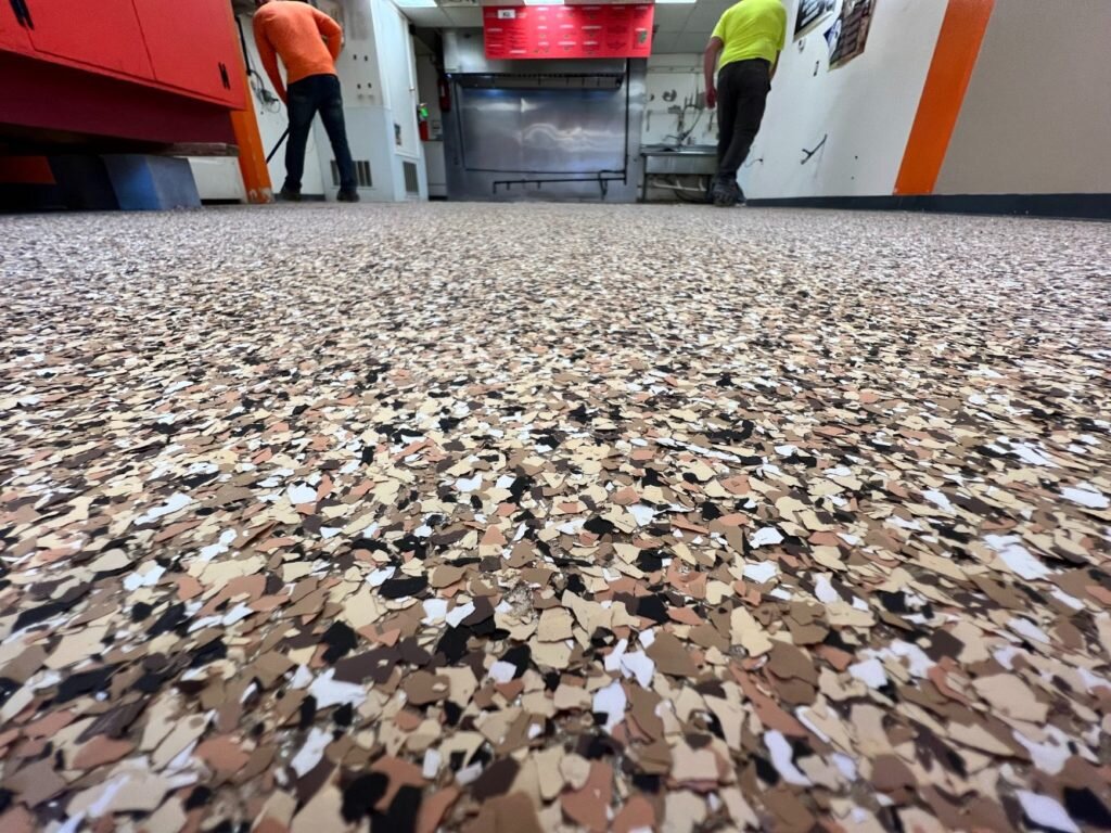 Buffalo Floor Coatings installer applying flake topcoat close-up